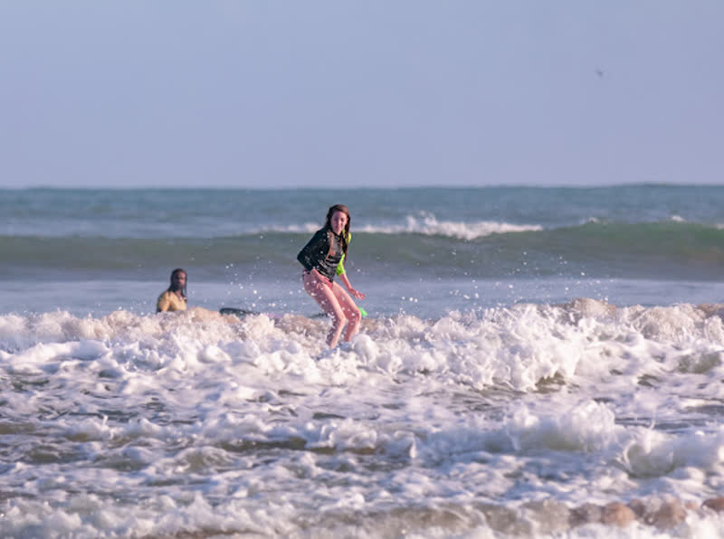 A beginner catching a whitewater wave during a surf lesson in Weligama